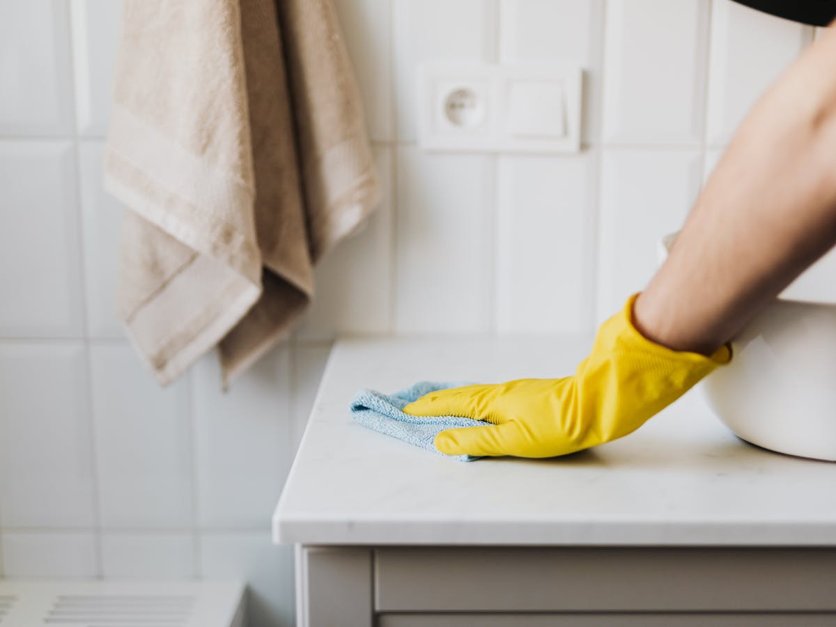 Hand mit gelbem Handschuh wischt Marmor sauber